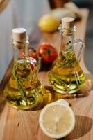 olive oil in glass bottles with lemon and tomato on wooden table photo