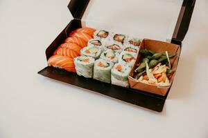 Sushi y rollos en un caja en un blanco fondo, japonés comida foto