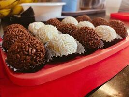 Close up of assorted chocolate truffles on a red tray. photo