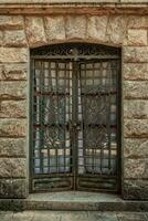 Old door with iron grille in the stone wall of the building photo