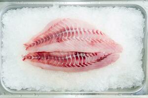 Fresh raw tilapia fish on ice in the supermarket, top view photo