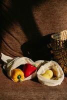 Still life with red and yellow peppers in a woven bag on a brown background photo