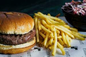 Beef burger with french fries and coleslaw on black background photo