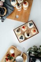 top view of delicious cupcakes with berries and cream on wooden cutting board photo