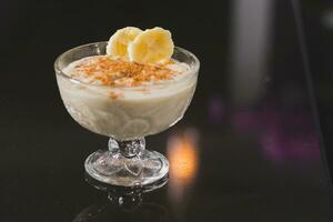 vanilla pudding with butter and cinnamon in a glass on a black background photo