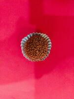 Coffee beans in paper cup on pink background, top view photo