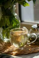 Green tea in a glass cup and teapot on the windowsill photo