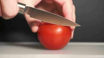 4K footage of slicing tomato on white cutting board against black background video