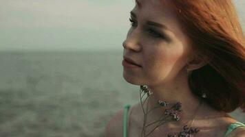 Portrait. Slow-motion shooting. Beautiful sexy girl with red hair in a dress posing against the sea background video