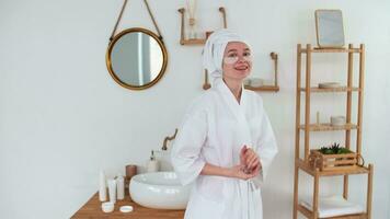 Skin Care, After Bath, Cosmetics at Home, Caucasian Woman, Anti Aging. Caucasian woman in robe and towel on head uses eye patches while standing in bathroom and smiling video