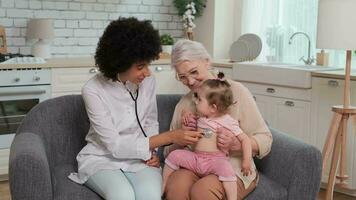 afro americano mujer médico mientras examinando familia de abuela y pequeño nieta. familia doctor, paciente apoyo, ayuda a hogar, cuidando para el enfermo. video