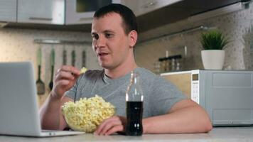 blijven Bij huis, vrije tijd Bij huis, online technologieën, zelf isolatie, huis aan het kijken films. een Mens aan het kijken films terwijl zittend Bij huis gebruik makend van een laptop aan het eten popcorn en drinken Frisdrank. video
