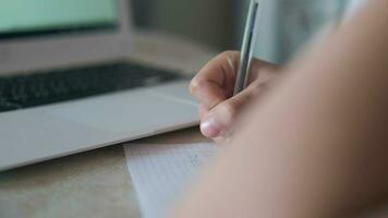 Close-up of hands with a fountain pen, laptop. A child writes in a notebook doing homework while sitting at a desk. Left camera movement video