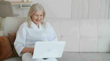 pelle cura, anziano donna, casa cosmetici, anziano età, cosmetico procedure. anziano donna saluta agitando amici utilizzando il computer portatile. in linea comunicazioni video