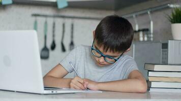 online aan het leren, afstand les, onderwijs Bij huis, technologie voor kinderen. jongen met leerboeken aan het doen school- huiswerk en gebruik makend van digitaal tablet computer Bij huis. 4k video