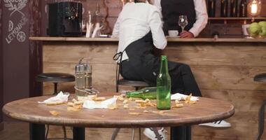 smutsig restaurang tabell efter en upptagen dag. anställda avkopplande i de bakgrund medan de tabell är inte rengöras än. rörig restaurang tabell. video