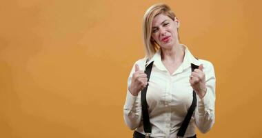 Young blonde woman in white shirt and black suspenders cheering and being happy. Pretty stylish woman glad to win a prize. Feeling victorious. video