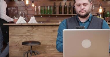 Man in a local coffee shop makes a phone call while drinking coffee. Working remotely as a freelancer on his business. video