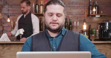 joven empresario en un pequeño café tienda bebidas café durante un vídeo llamar. teniendo un conversacion con su colega en el ordenador portátil mientras trabajando remotamente video