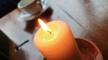 A candle flame moves gently in the wind on a table in warm light. video