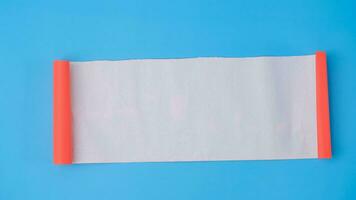 An orange rolled square paper is spread out into a blank white sheet on a light blue background. Crumpled blank white paper with copy space for text or advertising space. photo