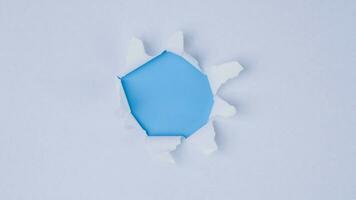 un pedazo de papel Rasgado desde el centrar revelador un azul antecedentes. foto