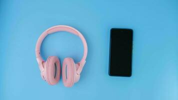 Mobile phone and headphones on blue background. Wireless technology and equipment concept. photo