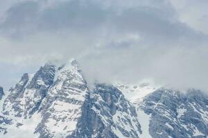 rocky snowy mountains with dense fog and clouds on the sky photo