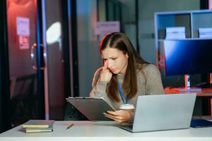 Business woman drinking coffee to get some energy for working overtime sitting at desk using computer and doing overtime photo