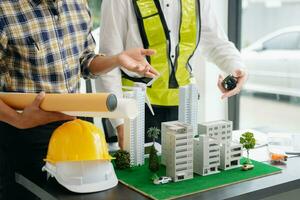 ingeniero trabajo en equipo reunión, dibujo trabajando en Plano reunión para proyecto trabajando con compañero en modelo edificio a oficina. asiático industria profesional equipo foto