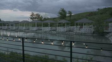 a lake with a fence and umbrellas in the background video