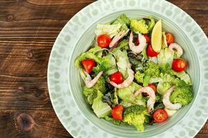 Bowl of salad with broccoli and shrimp. photo