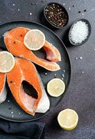 Stake Fish trout with lemon and spices on dark background photo