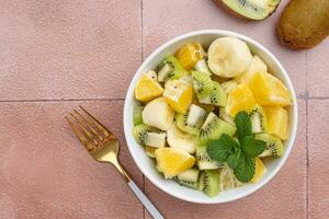 Bowl of healthy fresh fruit salad on ceramic background photo