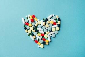 heart shape made of different pills on blue background photo