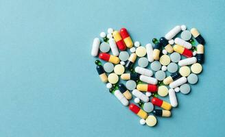 heart shape made of different pills on blue background photo