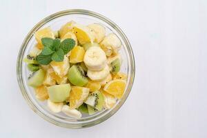 Bowl of healthy fresh fruit salad on white background photo