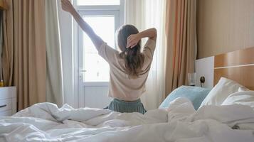 Woman stretching in bed after wake up, back view photo