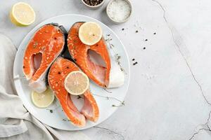 Stake Fish trout with lemon and spices on cement background photo