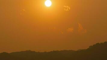 Zeit Ablauf von das Sonne Rahmen Über Hügel Das sind bedeckt mit Wolken, im das Stil von rauchig Hintergrund. video