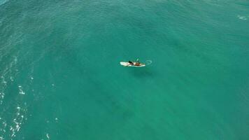 Aerial view of surfgirl rowing on surfboard. Woman in ocean during surfing. Surfer on board and ocean waves video