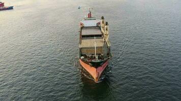 Cargo rusty ship sails on the sea at sunset. Drone view video