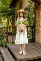 Modest preteen girl standing on country house threshold with basket of wildflowers photo