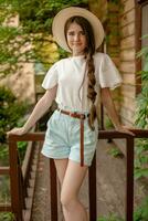 Smiling tween girl standing on wooden threshold of rural house in summer photo