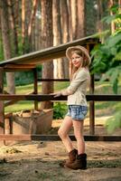 Smiling tween girl standing near animal stall in country estate in forest photo