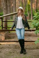 Teenage girl standing near outdoor stable in country estate in forest photo