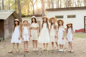 Preteen girls in light dresses standing in backyard of country house in forest photo