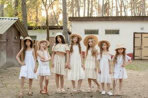 Friendly tween girls standing on courtyard of country house in pine forest in summer photo