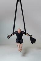 atlético hombre en un negro deporte traje es ejecutando un acrobático elementos en un estudio. foto