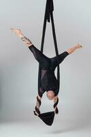 atlético hombre en un negro deporte traje es ejecutando un acrobático elementos en un estudio. foto